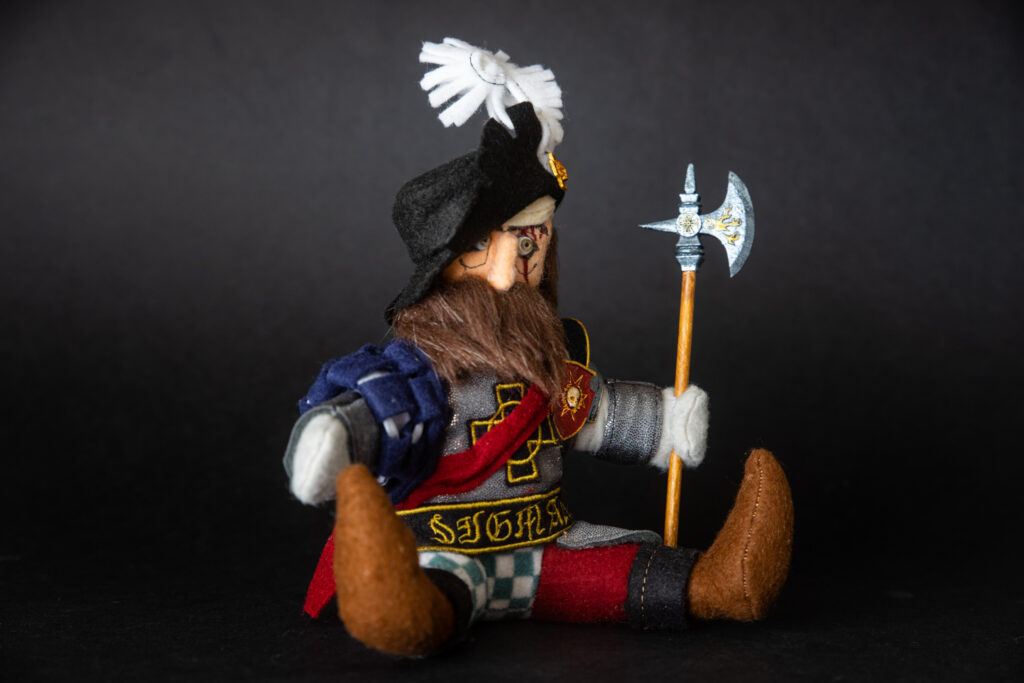 The Jongleurs Dream presents Markus Kruber, the stalwart Empire soldier and beloved hero of the Warhammer world, now reimagined as a premium plushie collectible. This detailed desk display piece captures his rugged charm and iconic warrior stance in soft fabric form