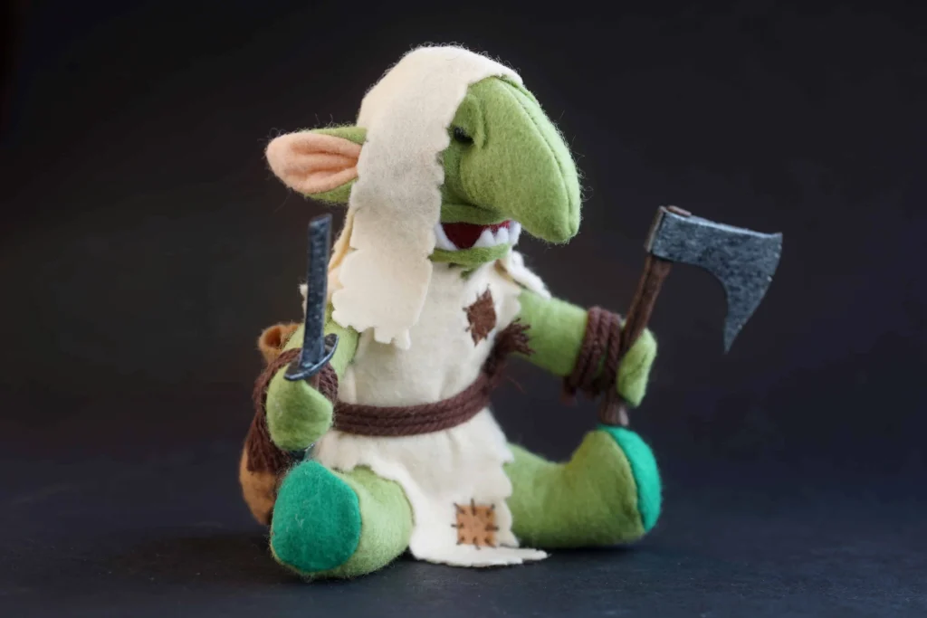 The Jongleurs Dream presents a Gnoblar plush collectible - A cuddly version of the small green-skinned creatures, featuring their large ears and noses. This soft toy is perfect for fans of the fantasy realm of grimdark and collectors of miniature tabletop figures.