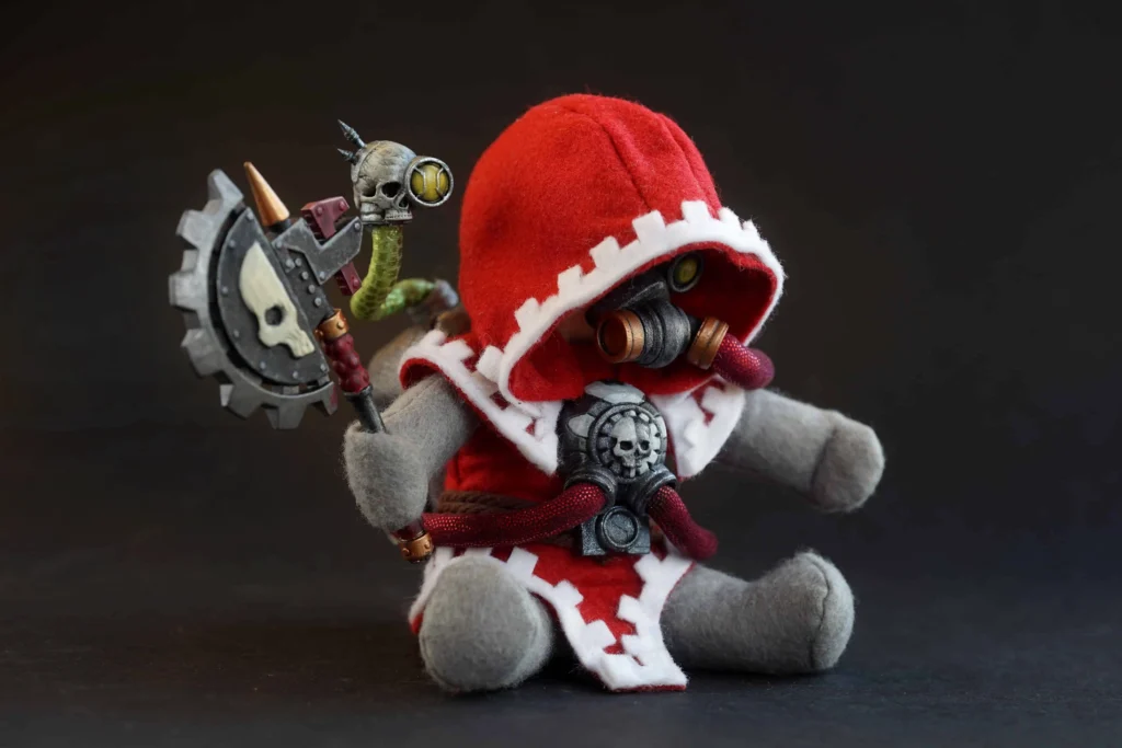 The Jongleurs Dream presents an Enginseer plush collectible - A cuddly version of the Adeptus Mechanicus engineer, clad in red robes and equipped with mechanical augmentations, performing maintenance on a battlefield vehicle. This premium soft toy is perfect for fans of sci-fi tabletop games and collectors of plush figures inspired by tactical games and legendary sagas.